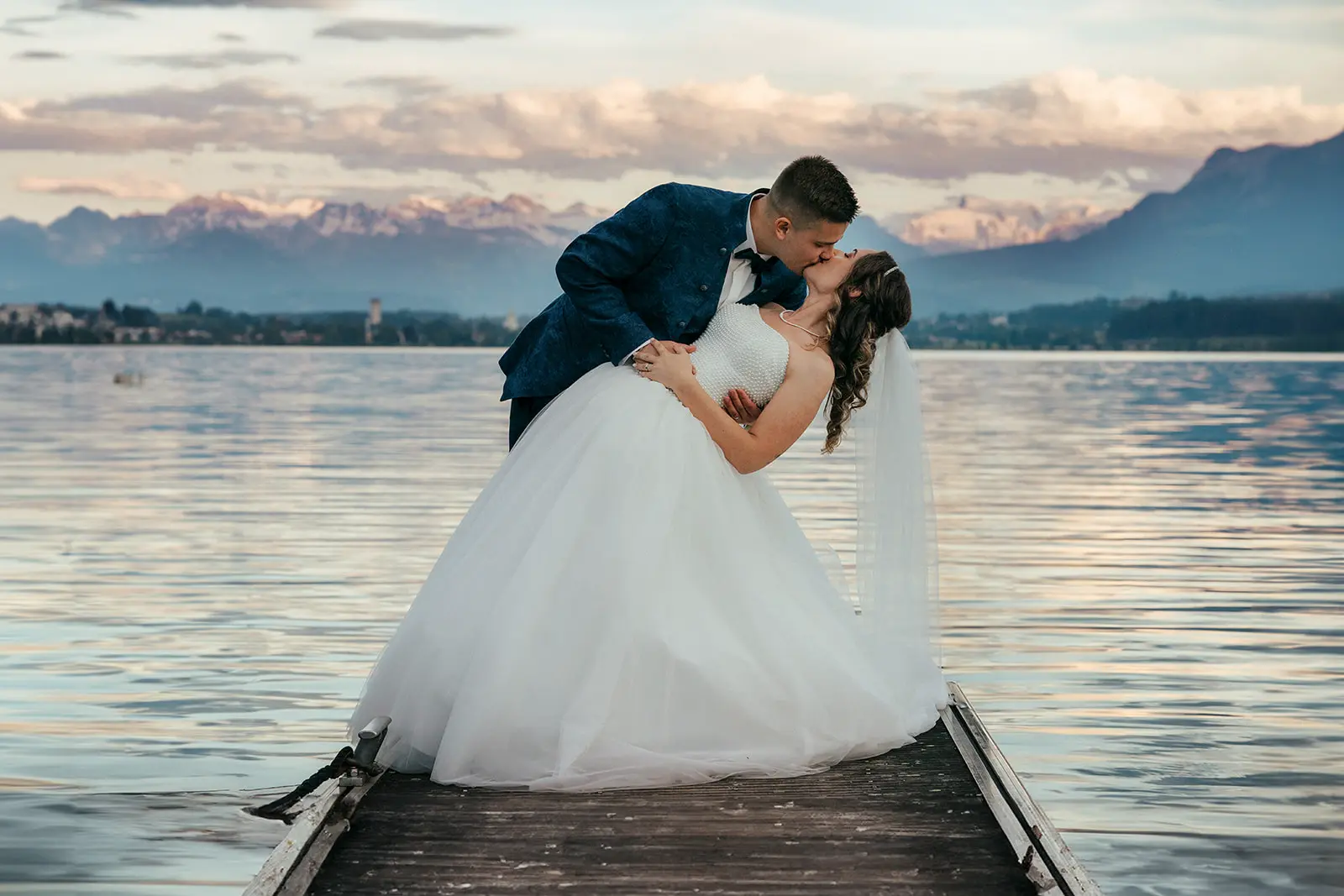 Brautpaar auf einem Steg am Sempacher See mit Alpen im Hintergrund in der Schweiz